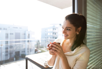 Wall Mural - Woman relaxing on balcony holding cup of coffee or tea