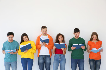 Canvas Print - Group of people reading books while standing near light wall