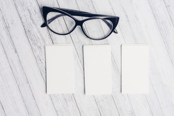 Business cards on a wooden background and glasses with a dark frame