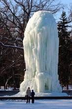 People Looking At Frozen Fountain In A Park. Kharkiv, Ukraine