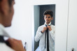 © Justin - Young business man getting ready in mirror