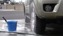 A Person Rinses Off Freshly Washed, Soapy Tires While Cleaning His Vehicle.