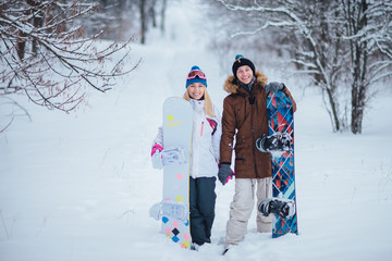 two happy snowboarders in winter forest