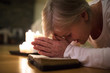 © Halfpoint - Senior woman praying, hands clasped together on her Bible.