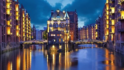Fototapete - House and two brides in the evening in Speicherstadt district, Hamburg, Germany  (static image with animated sky and water)
