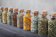 Different Kinds Of Herbs For Tea Inside Glass Bottles.