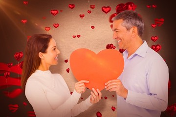 Canvas Print - Composite image of smiling couple holding heart shape paper