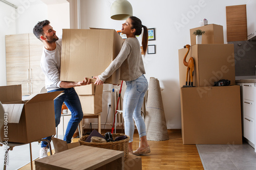фотография  Young couple carrying big cardboard box at new home.Moving house.