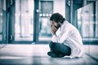 © vectorfusionart - Worried doctor sitting on floor