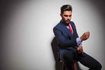 Poster - seated elegant man in suit is gesturing while looking down