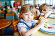 © Irina Schmidt - Cute healthy preschool boy eats hamburger sitting in school canteen