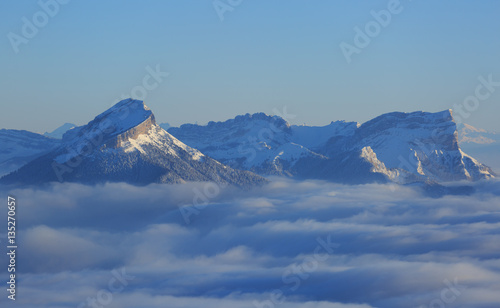 Fotografía The snow covered Chartreuse mountains rising out of the clouds on a winter morning