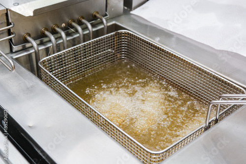 Cuadros en Lienzo The cook fries meat in a deep fryer.