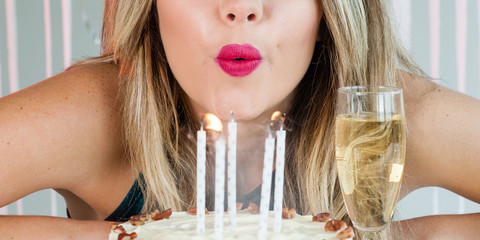 Wall Mural - Pretty girl blowing out celebration candles on delicious cake