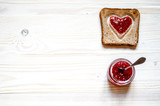 Fototapeta Mapy - Toasted white bread with a heart inside. At the heart plastered with raspberry jam. Under the croutons is a jar of jam, a jar of sticks dessert spoon.