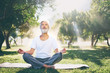 © luengo_ua - Yoga at park. Senior bearded man in lotus pose sitting on green grass. Concept of calm and meditation.