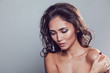 © kanashkin - Brunette girl with shiny wavy hair and beautiful make up posing at studio on grey background.
