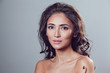© kanashkin - Brunette girl with shiny wavy hair and beautiful make up posing at studio on grey background.