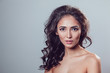 © kanashkin - Brunette girl with shiny wavy hair and beautiful make up posing at studio on grey background.