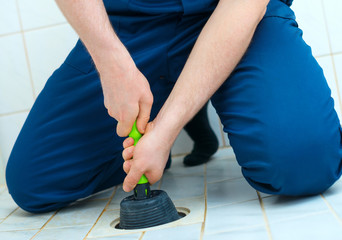 Wall Mural - Plumber repairing bathroom with hand plunger.