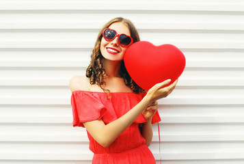 Pretty smiling woman in red dress and sunglasses with air balloo