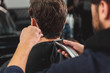 Hairdresser cutting male hair by machine