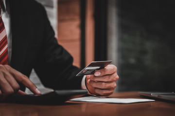 businessman holding credit card and using calculator in his offi