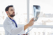 Smart male general practitioner looking at radiograph