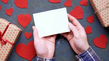 Wall Mural - Gentleman's hands holding romantic postcard Valentine's Day holiday concept of gentle couple love gift on vintage blue background. Flat lay top view, blank empty space for tracking text and design