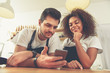 © Yakobchuk Olena - Happy couple looking at mobile in cafe