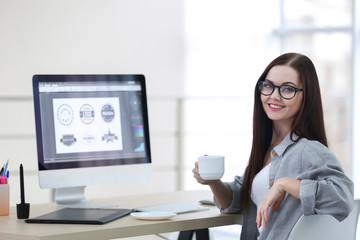 Canvas Print - Young beautiful designer drinking coffee in office