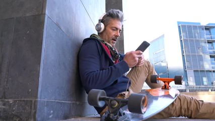 Wall Mural - Skateboarder sitting in urban area listening to music