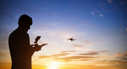 Wall Mural - drone pilot with quadrocopter. silhouette against the sunset sky