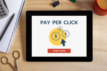 Pay Per Click (PPC) concept on tablet screen with office objects on wooden desk. All screen content is designed by me. View from above.