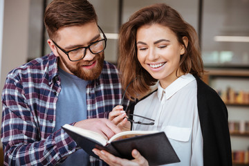 Wall Mural - Two happy young students studying together in public library