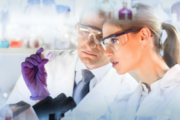 Poster - Attractive young scientist and her post doctoral supervisor looking at the microscope slide in the forensic laboratory.