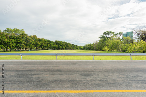 Fotomural Side view of asphalt road with park in city