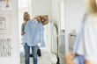 © Maskot - Teenage girl looking in mirror while holding shirt at bedroom