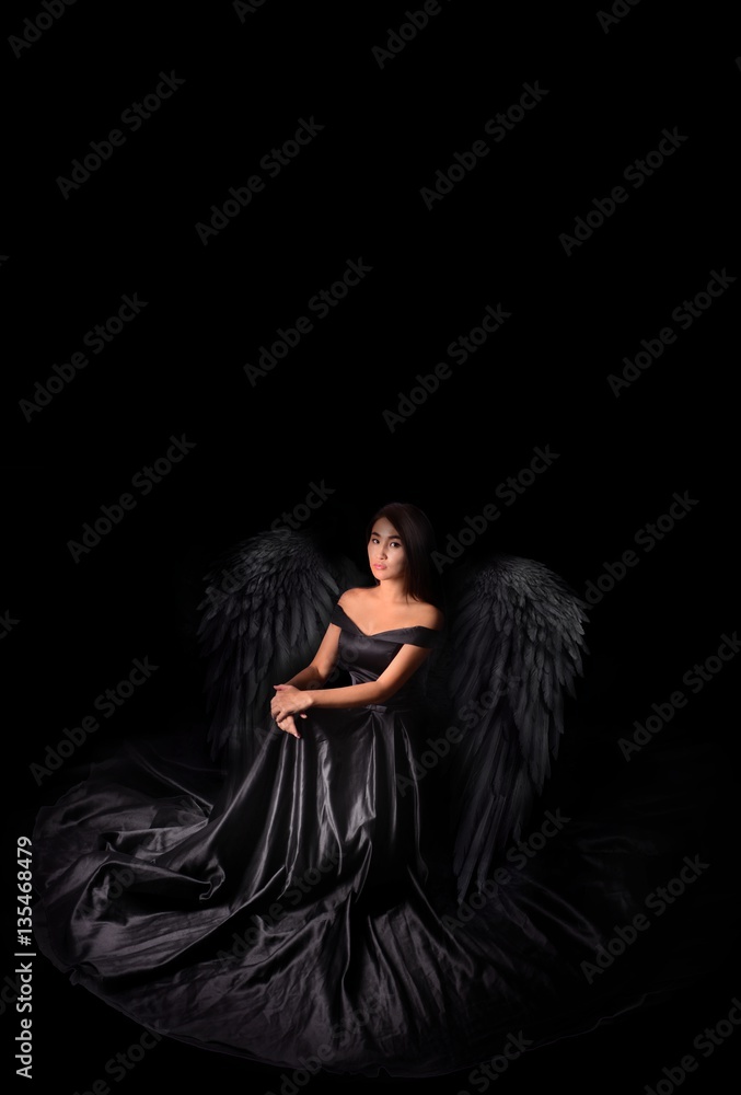 Angel-devil model in black long dress with wings sitting in studio. Black background, Stock Photo | Adobe Stock Angel-devil model in black long dress with wings sitting in studio. Black background, Stock Photo | Adobe Stock