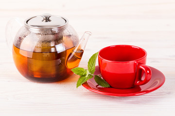 Teapot and red cup on wooden table