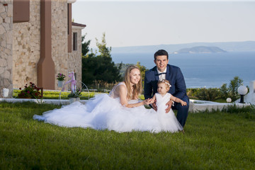 Summer wedding with children. Happy bride and groom in wedding day with little daughter.