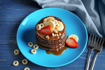 Sticker - Blue plate with delicious chocolate pancakes decorated with strawberry and banana on wooden table