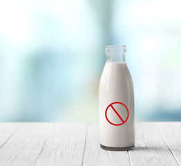 Canvas Print - Allergic food products concept. Glass bottle of milk with restriction sign on blurred background