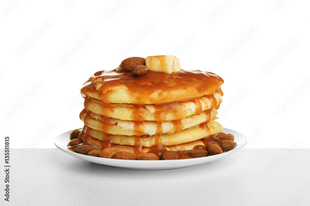 Tasty pancakes with almonds and caramel syrup isolated on white