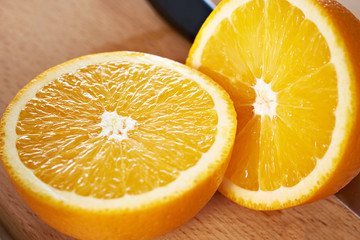 Wall Mural - Juicy bisected oranges closeup on wooden board