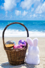 Easter Bunny With Basket And Color Eggs On The Ocean Beach