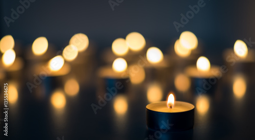 Cuadros en Lienzo Flame of many candles burning on the background blue color