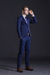 © Acronym - Young and confident business man. Businessman in suit over dark background.