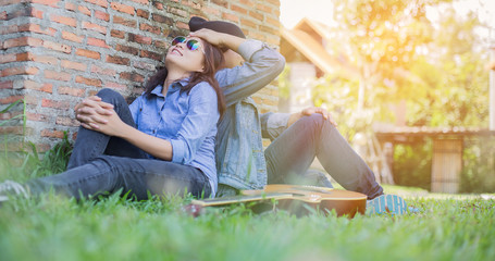 Poster - Hipster man playing guitar for his girlfriend outdoor against br