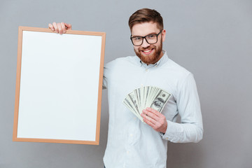 Wall Mural - Happy young bearded businessman holding copyspace board and money
